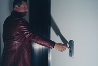 Man in leather jacket pressing button for lift