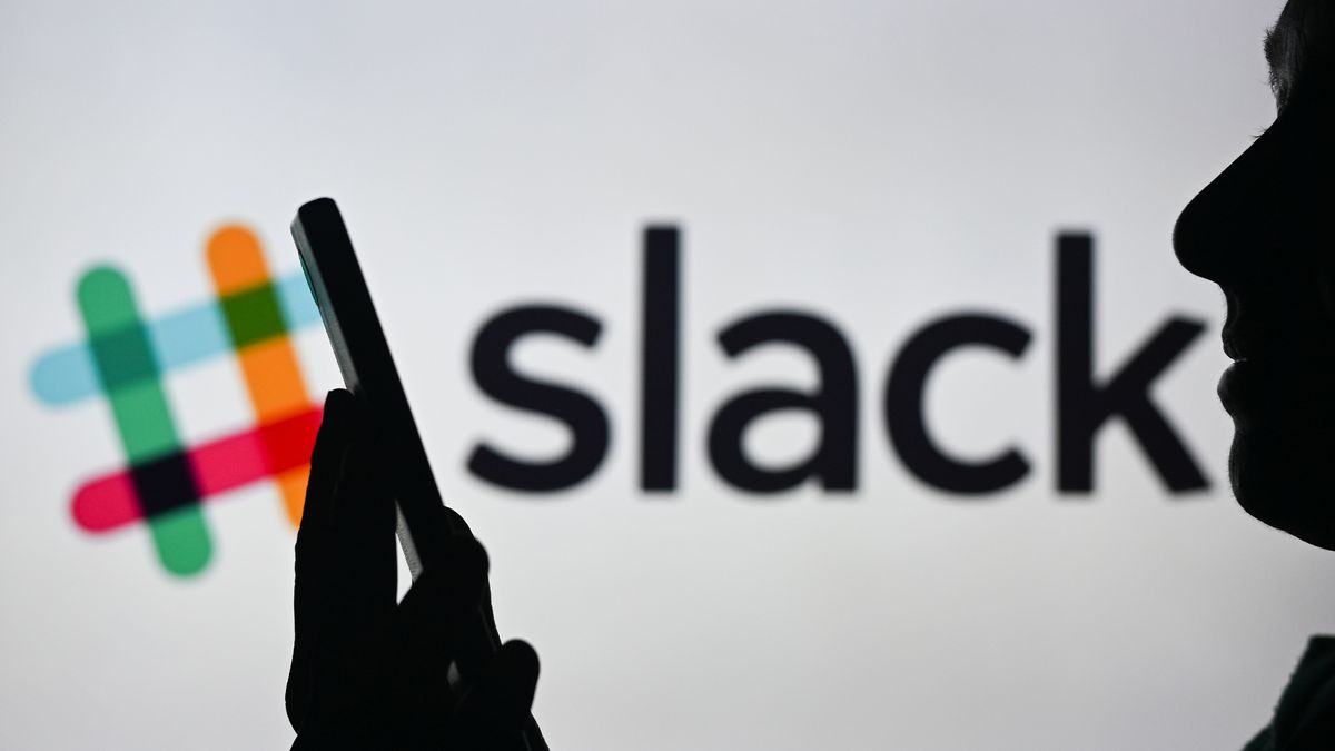 An image of a woman holding a cell phone in front of the Slack logo displayed on a computer screen.