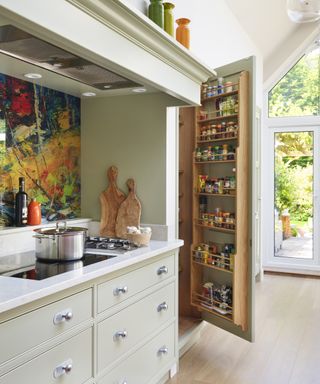 A traditional, neutral kitchen with a tall cupboard that has a spice rack built into the door.