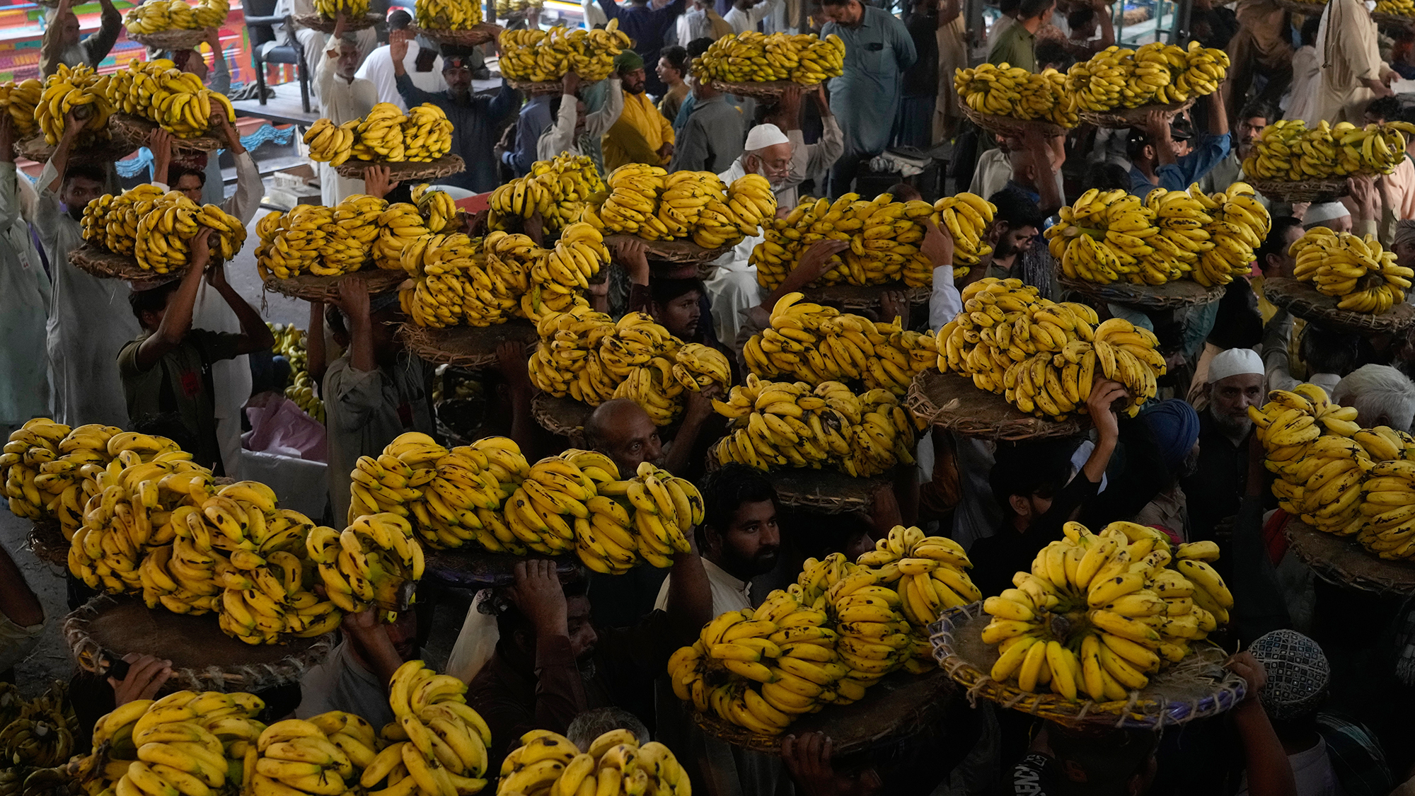 A group of fruit traders carry bananas to a market in Lahore, Pakistan