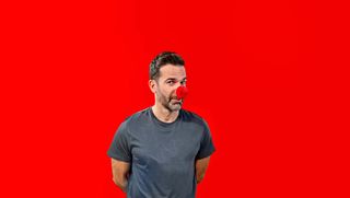 Gethin Jones stands in front of a red background wearing a Red Nose