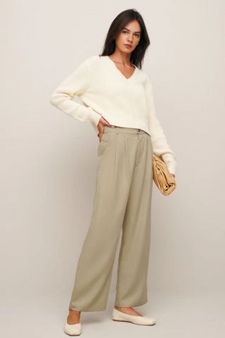 reformation winter sale woman wearing beige wide leg trousers with cream flats and jumper