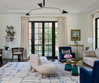 Cream living room with large windows and blue velvet seating