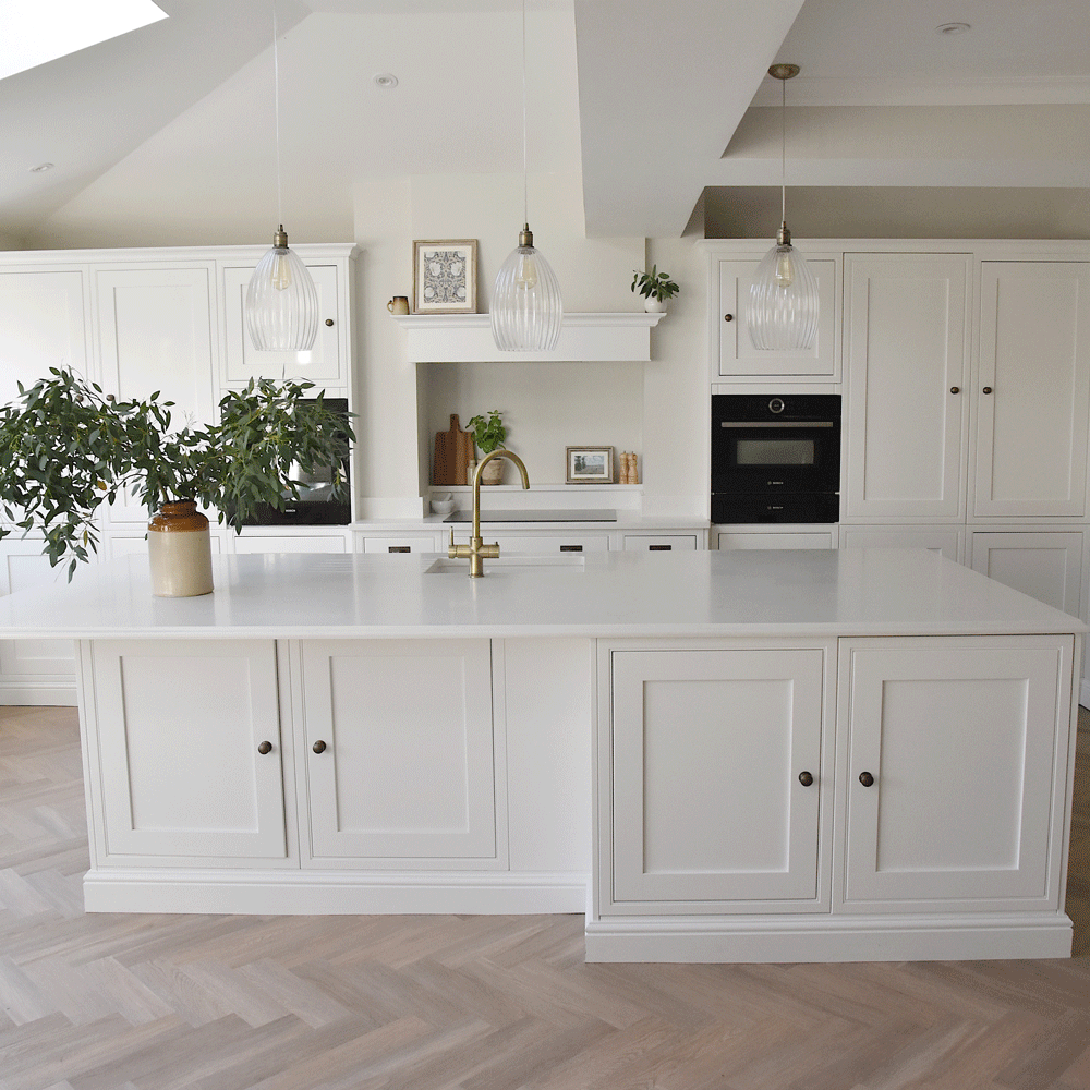 white kitchen island with gold tap and lots of cupboards