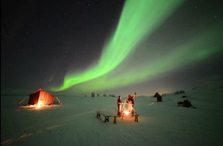 Northern lights glow over skywatchers high in the Swedish mountains on Feb. 21, 2014 in this image from the video "Lights Over Lapland" by Chad Blakley.