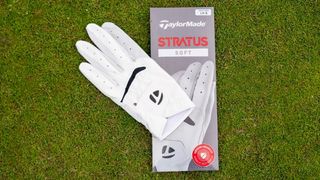 The TaylorMade Stratus Soft Glove lying on the ground next to the packaging