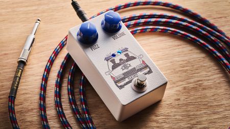 Funny Little Boxes Caught By The Fuzz: inspired by Supergrass, this two-knob fuzz has a white enclosure, blue dials, and a comic graphic of someone being apprehended in a police car.
