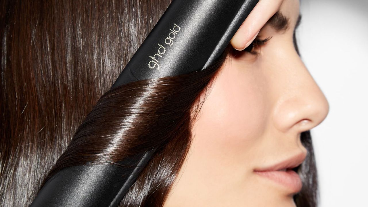 ghd deals - woman curling her hair with the ghd gold striaghteners