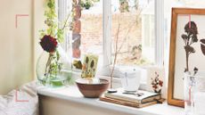 Windowsill with vase of flowers, stack of books, candle and photo frame