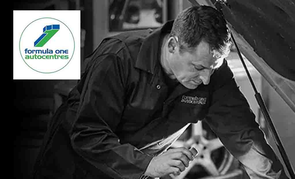 F1 autocentres logo placed over a black and white image of a man fixing a car
