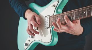 A guitarist plays an offset guitar