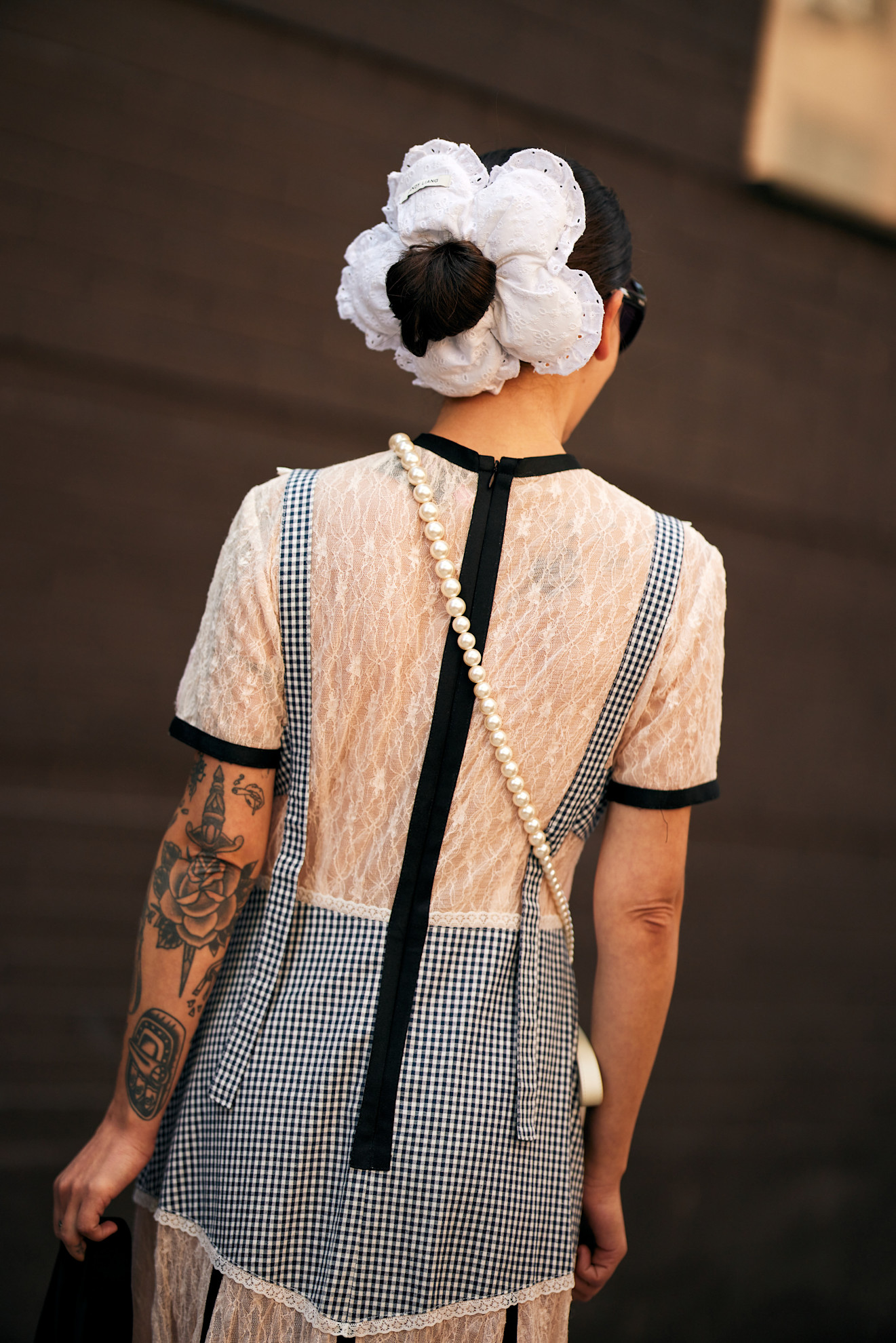 a woman wearing a lace white dress with a large white scrunchie in her hair