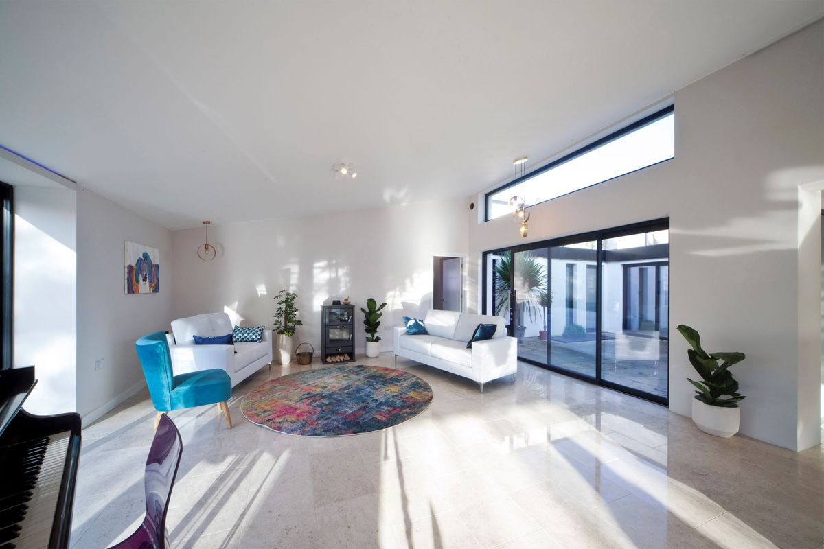 The inside living room is well lit with the tall windows with a white interior