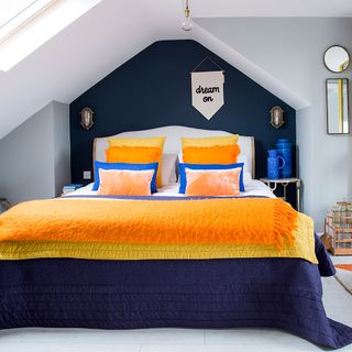 attic bedroom with bed and orange pillows