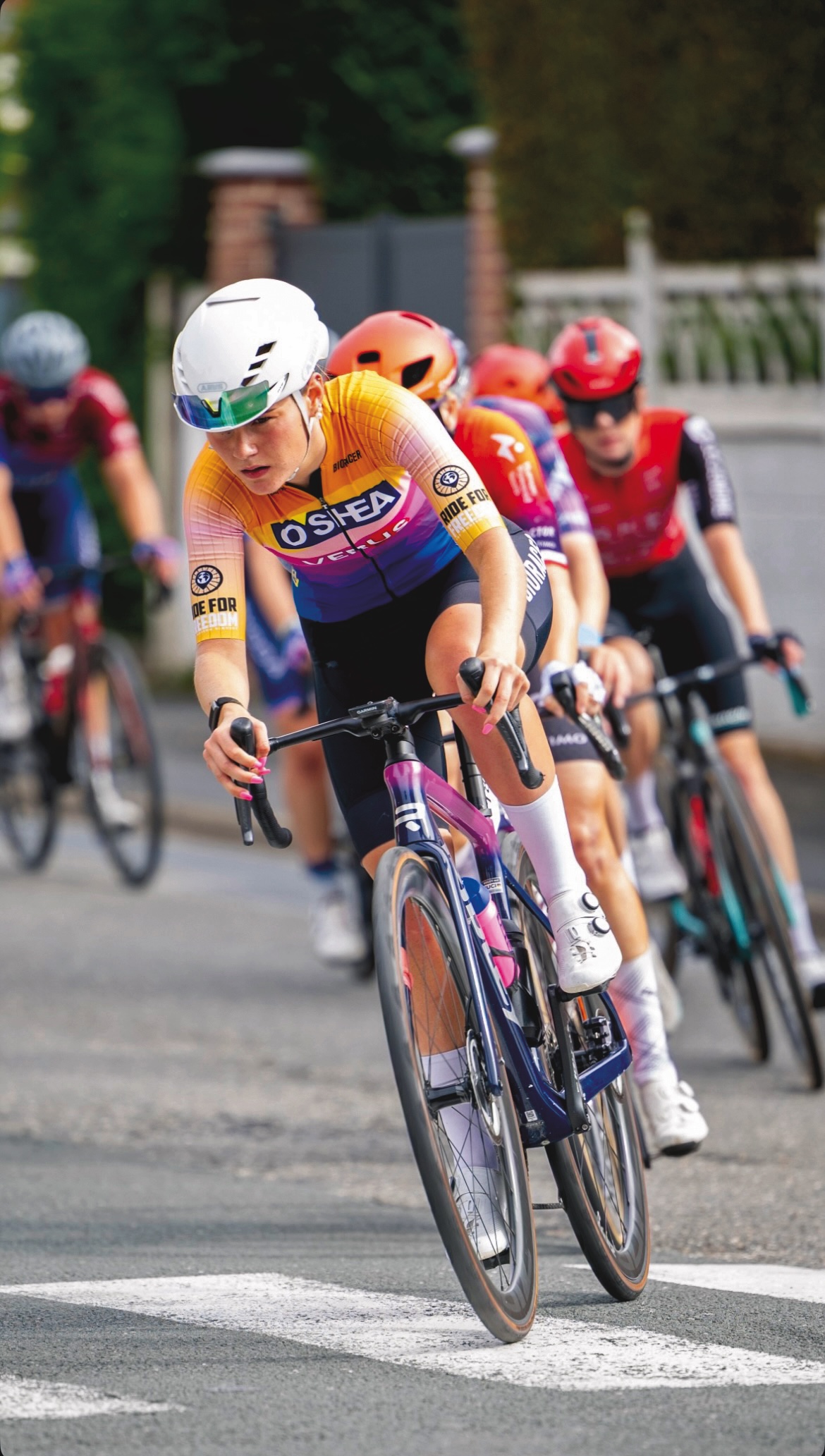 Grace Ward in orange O'Shea jersey competing in a road race