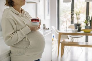 Unrecognisable pregnant woman has morning hot drink