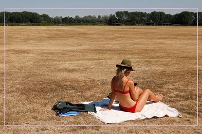 A woman sunbathing in a dry field