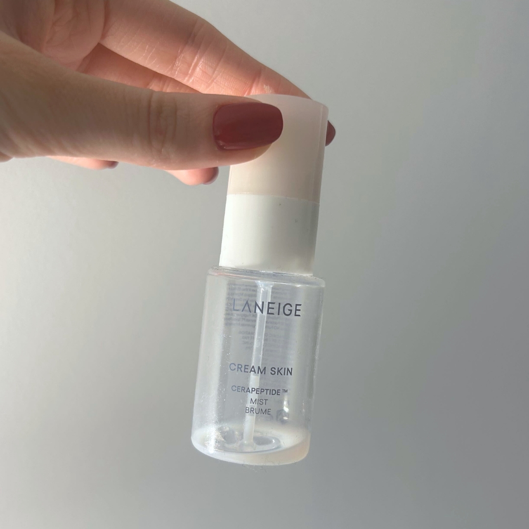 Hand, with short red nails, holding empty bottle of Laneige Cream Skin Cerapeptide Mist 30ml