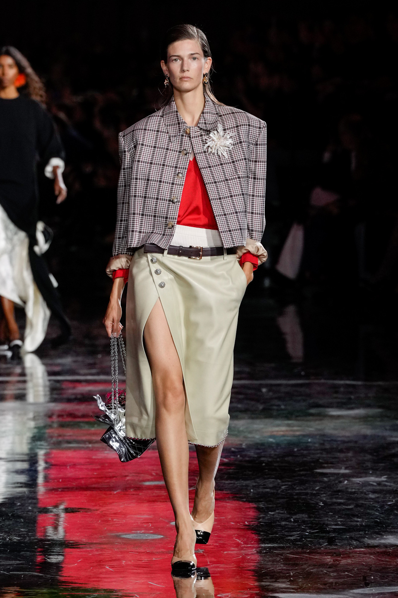 a model on the chanel runway wearing a pencil skirt with a plaid jacket and open chanel bag