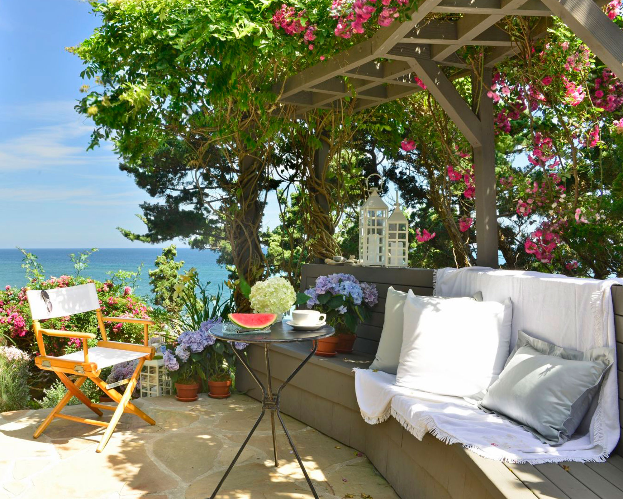 seaside patio with trellis covered with wisteria and roses, outdoor furniture and plants