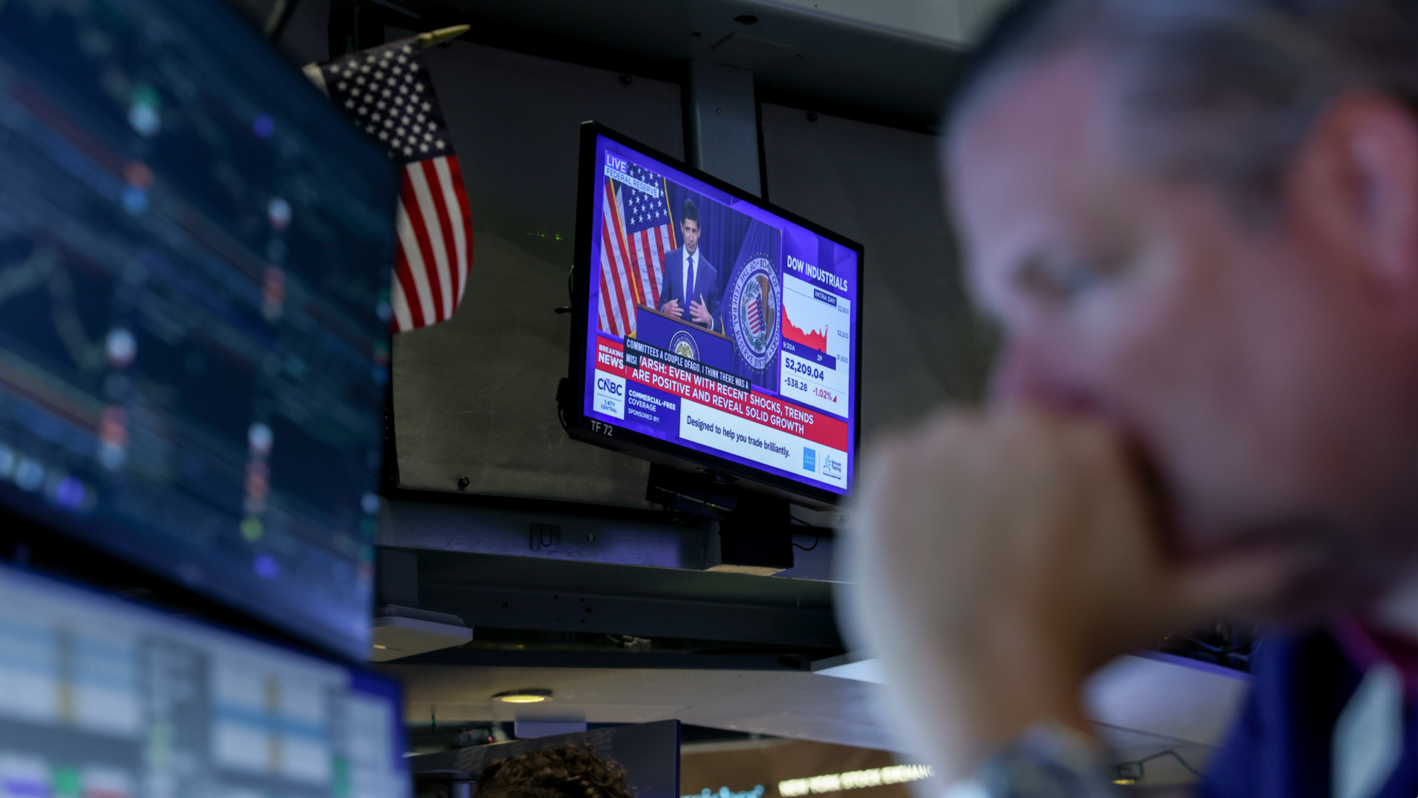 A television station broadcasts Kevin Warsh, chairman of the US Federal Reserve, speaking after a Federal Open Market Committee meeting as a trader works on the floor of the New York Stock Exchange.