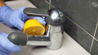 Using half a lemon to clean a faucet