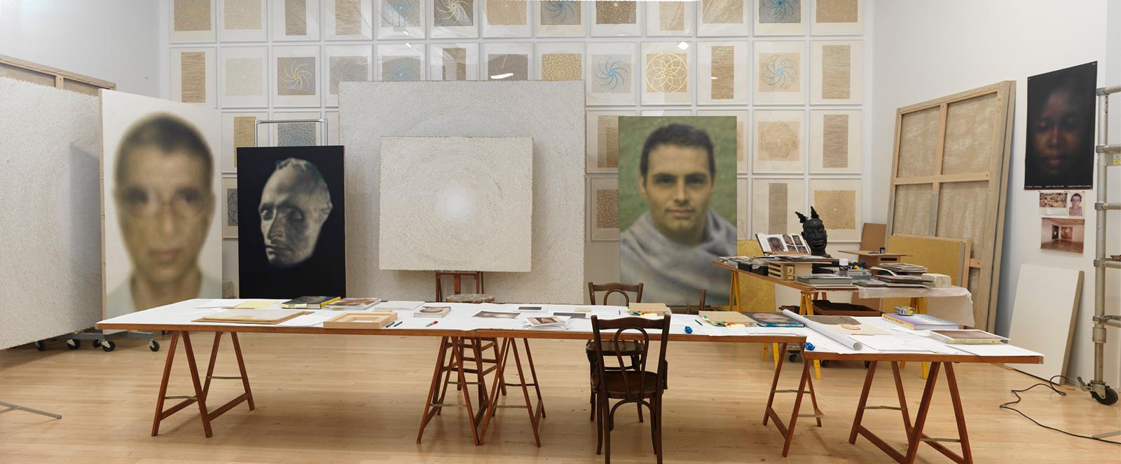 artist's studio with portraits, and artist materials on table