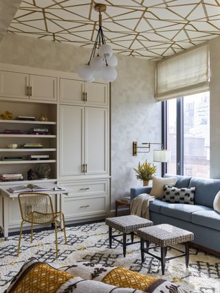 living room with textured wall, rug, ceiling wallpaper, beige cabinets and blue sofa