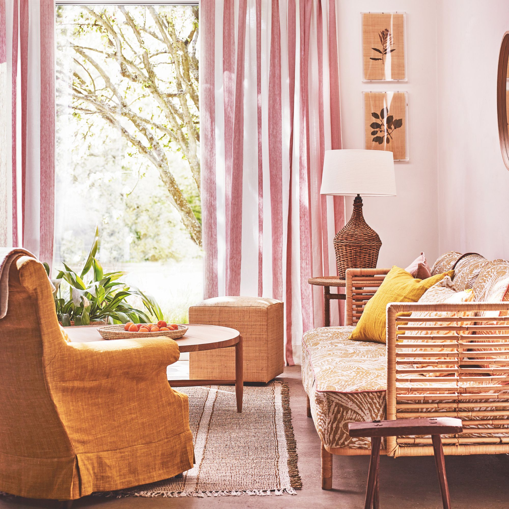 Wooden sofa frame with patterned cushions in a pink living room with striped curtains