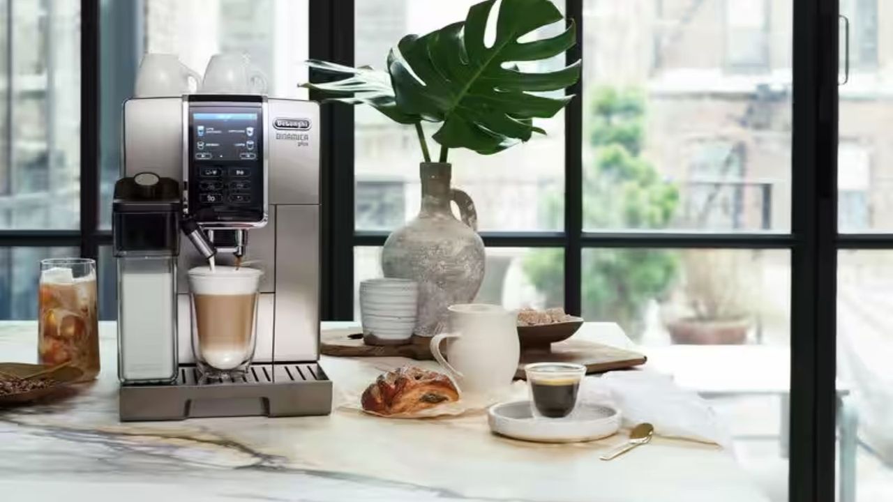 De&#039;Longhi Dinamica Plus Coffee Maker on a countertop with a full milk steamer and plants in the background