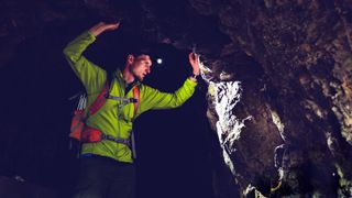 Man with headlamp exploring underground dark cave tunnel