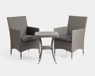 A rattan bistro set with two armchairs and a small glass-topped table