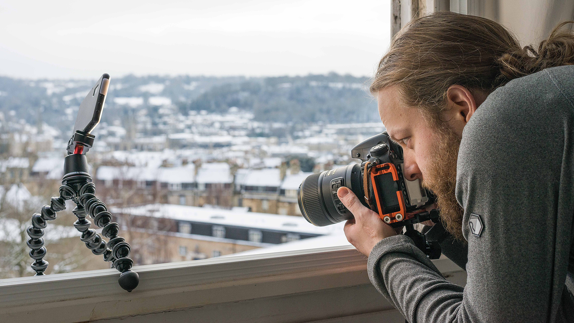 Man using Nikon D800 and Nikon 105mm macro lens to photograph frozen bubble on a snow-covered window sill next to Joby GorillaPod housing LED light panel