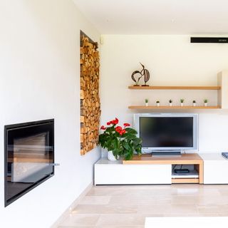 Tiled living space with cosy fireplace, many wooden logs and a television
