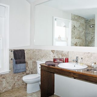 white bathroom with truffle coloured travertine tiles and washbasin