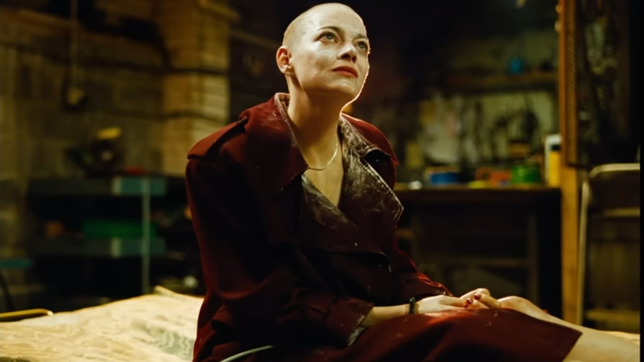 Emma Stone with shaved head looking devious in Bugonia.