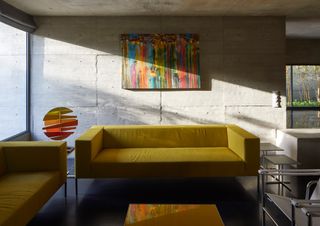 Living room with bright yellow sofa at Surat House by Matharoo Associates in India