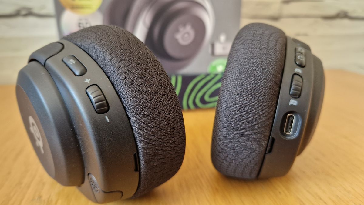 The SteelSeries Arctis 5X gaming headset on a wooden surface with the box in the background