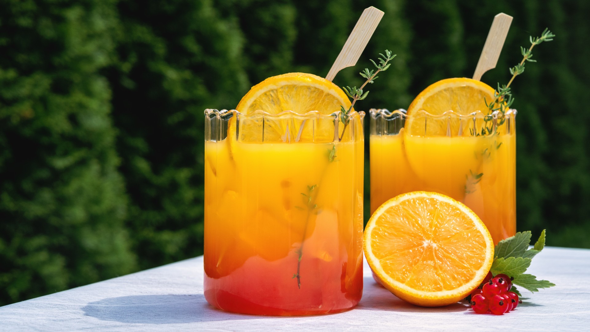 Two mocktail drinks with half an orange next to them close-up on a table outdoors
