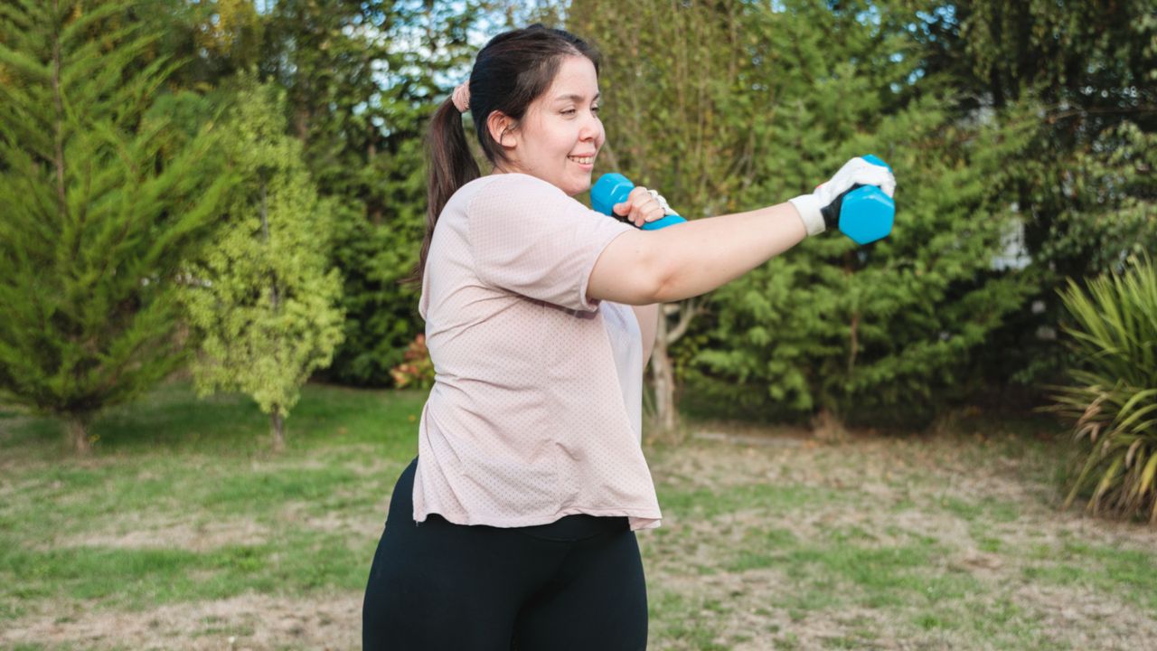 Woman doing standing core workout with dumbbells