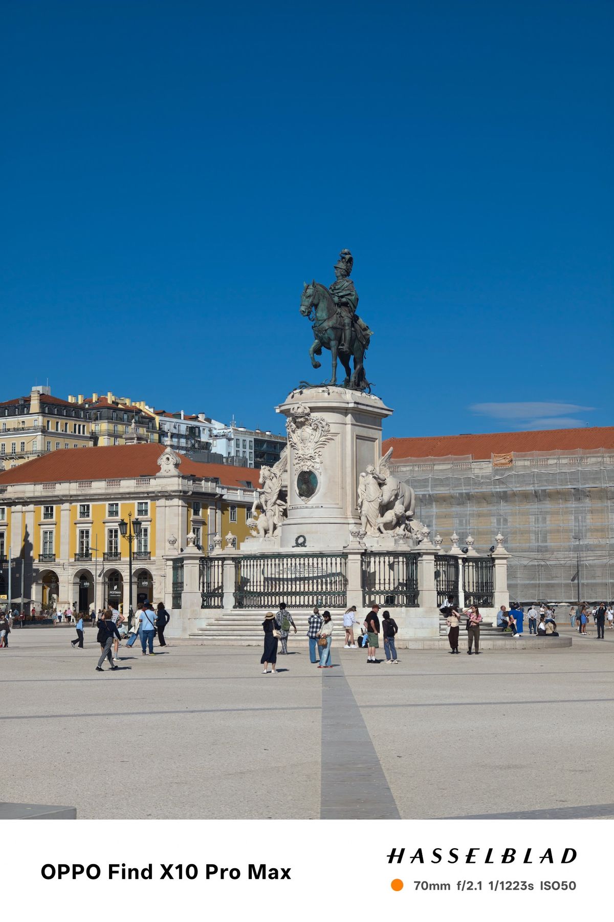 Equestrian statue in a large Lisbon square beneath a deep blue sky.
