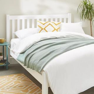 White bed frame with white bedding on top