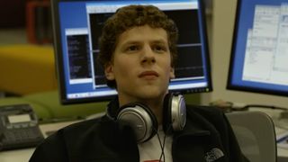 Jesse Eisenberg as Mark Zuckerberg wearing headphones around his neck in The Social Network. 