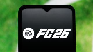 EA FC 26 logo displayed on a smartphone with the grass of a football pitch in the background