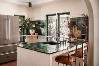 A kitchen with green zellige tiles on the counter