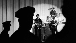 The Beatles onstage with policemen looking on
