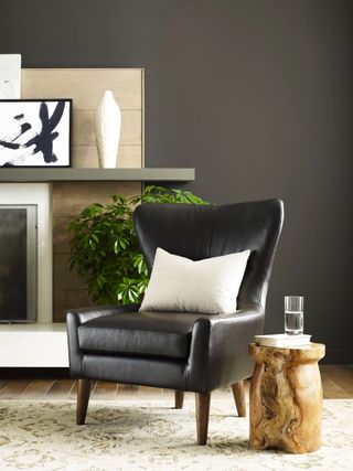 A living space with dark walls, a black leather chair, and a wooden side table