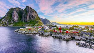 Popular view of Fishing hut (rorbuer) in Hamnoy, Norway with Lilandstinden mountain peak as the background during sunrise.