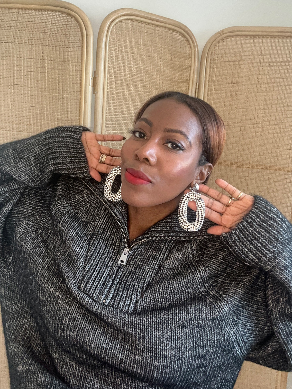 Tiffany Reid wearing statement earrings and a sweater from her fashion editor guide to holiday hosting.