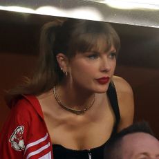 Taylor Swift wearing a choker necklace and kansas city chiefs jacket at arrowhead stadium
